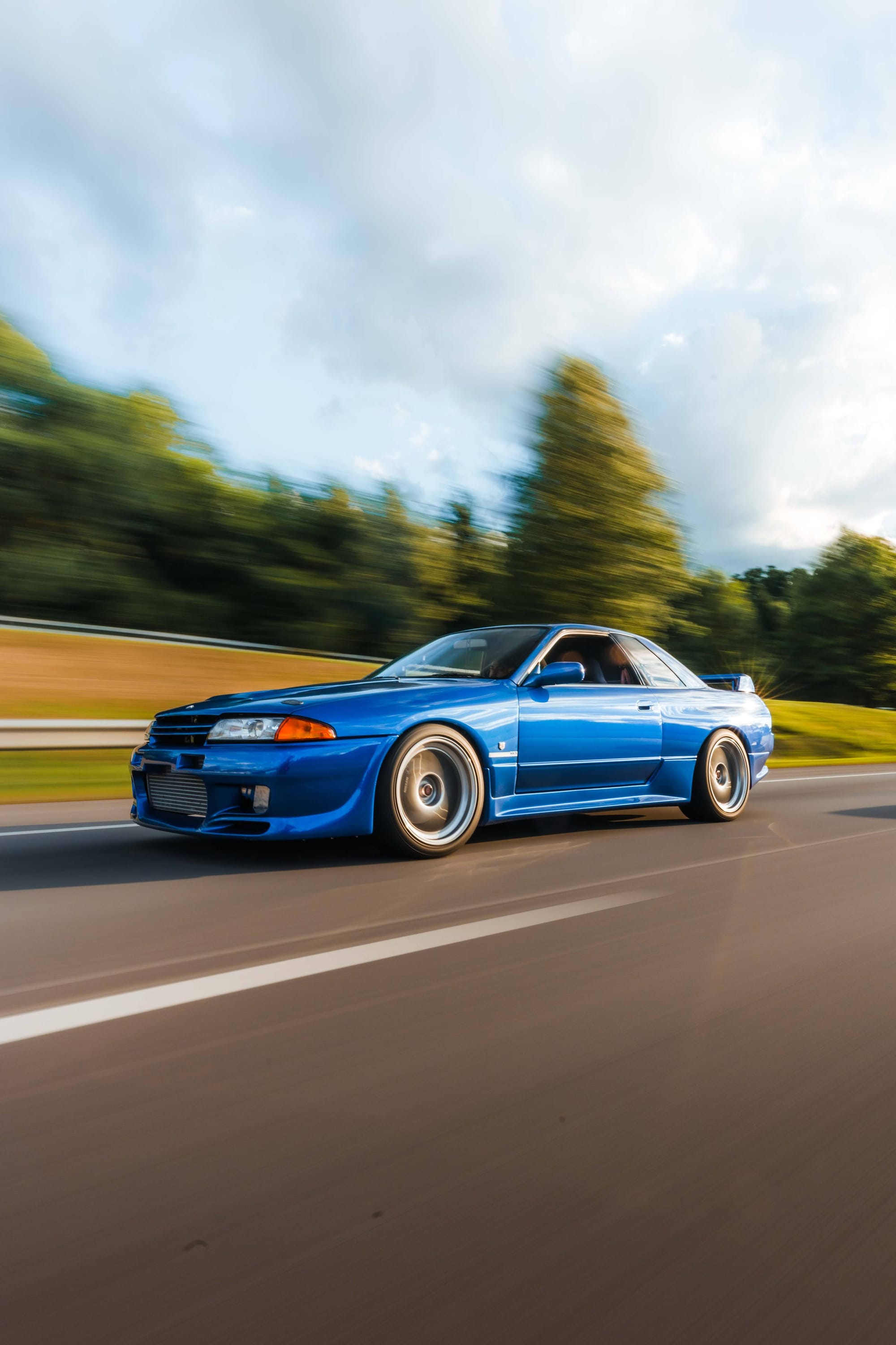 Blue Nissan Skyline R32 GT-R rolling shot on a Japanese country road