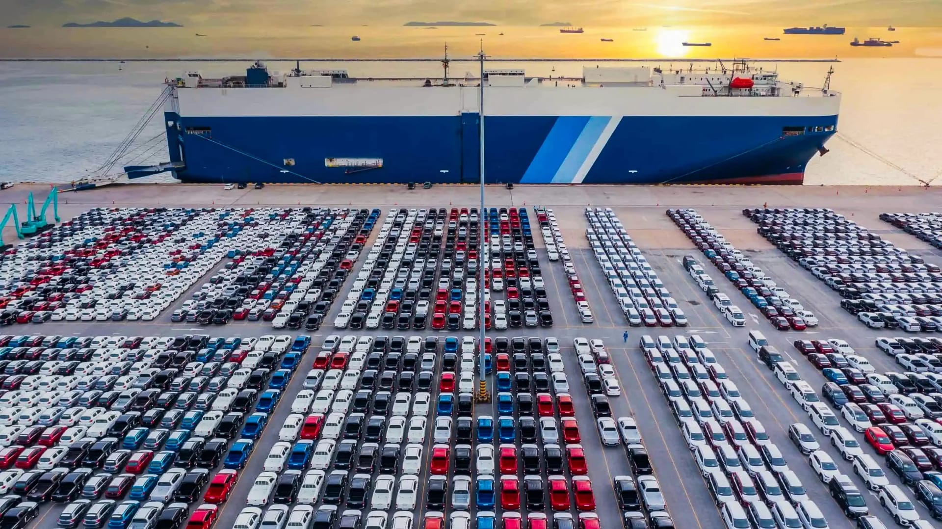 RoRo carrier at port with rows of export cars